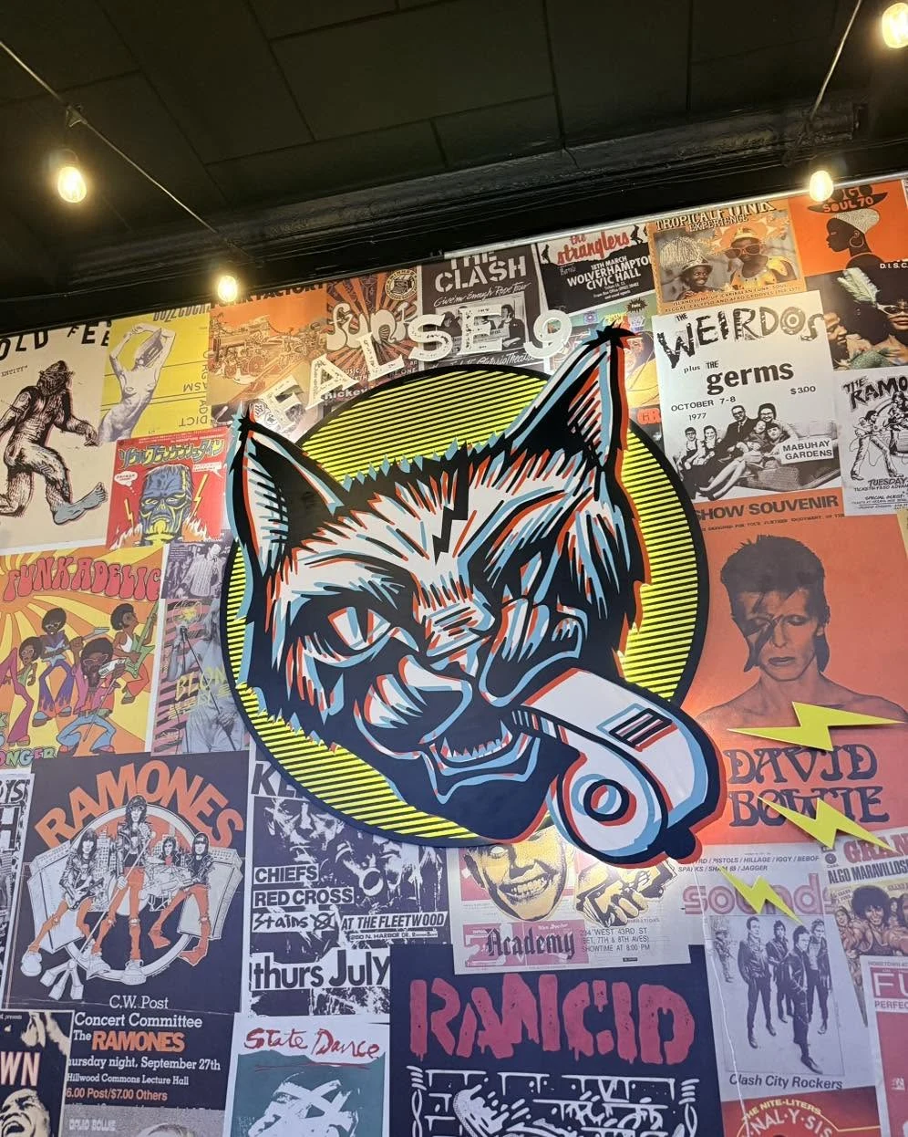 The False 9’s headphone cat mural against a wall of music posters